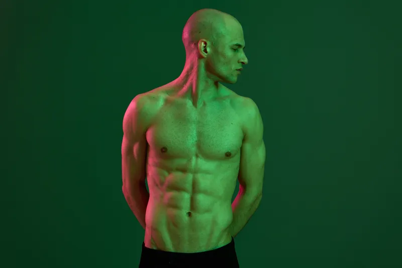 Green light highlighting a muscular man, showcasing strength and fitness. The image captures a unique artistic approach, evoking a sense of vitality and energy.