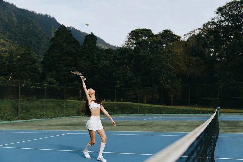 Female tennis player serving on a sunny day, showcasing athleticism and determination in a picturesque outdoor setting Emphasizing sports and wellness