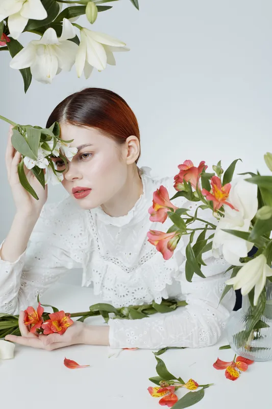 Elegant model with flowers against a minimalist background, expressing serene emotions, embodying beauty and nature in a spring inspired floral arrangement