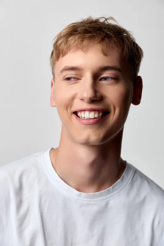 Smiling man in a white t shirt looks to the side, conveying a friendly casual vibe, cheerful mood and approachable style for lifestyle, fashion or corporate stock usage