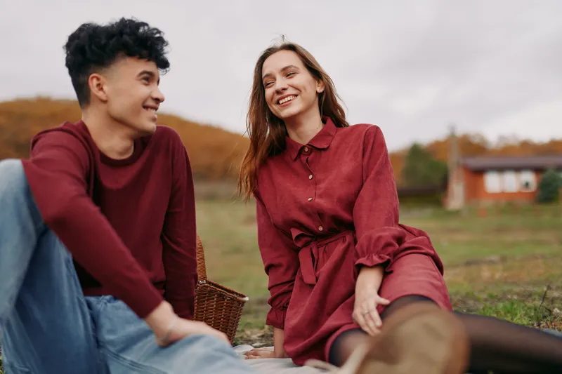 An authentic, candid moment between two friends outdoors, showcasing genuine connection, relaxed smiles, and natural emotion in a warm, sunlit field.
