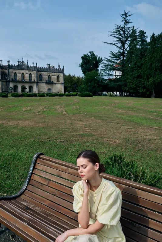 Woman on bench in park looking contemplative wearing light dress portrait with authenticity inclusivity and solitude