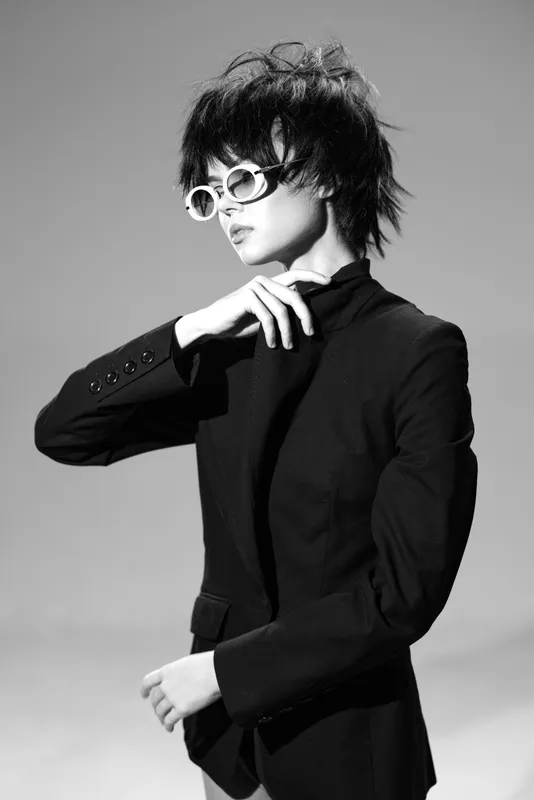 Stylish woman in black suit with sunglasses posing confidently in black and white portrait