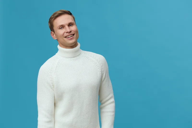 Smiling happy young caucasian man wear white turtleneck sweater look camera isolated on blue background digital detox mental health concept