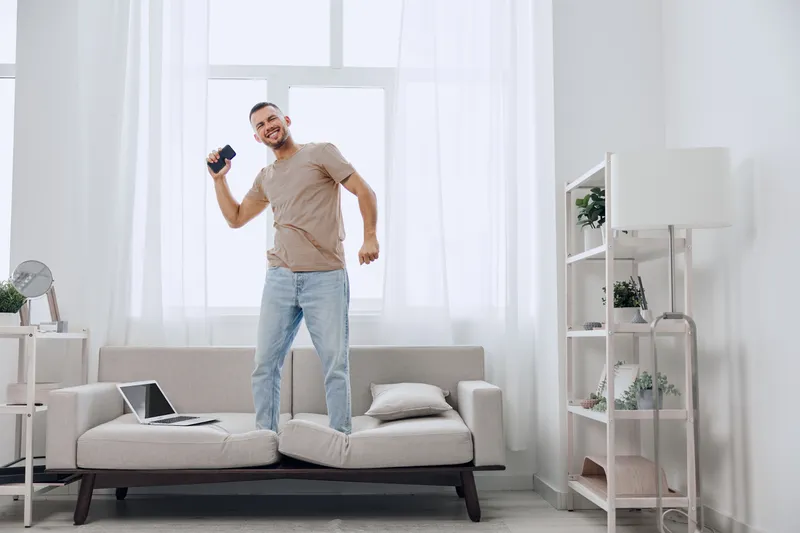 Man celebrating at home, enjoying a digital detox while connecting with his emotions and embracing authentic imperfection in a cozy living space.