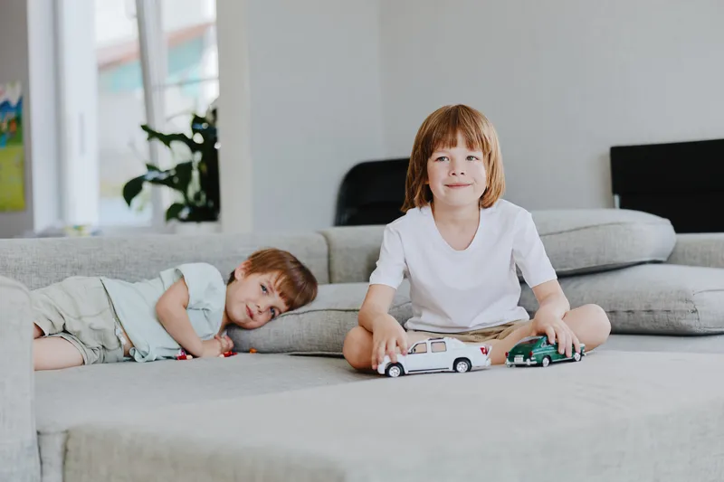 Happy children playing with toy cars in a cozy living room. The warm atmosphere is perfect for family activities, showcasing joy and creativity.