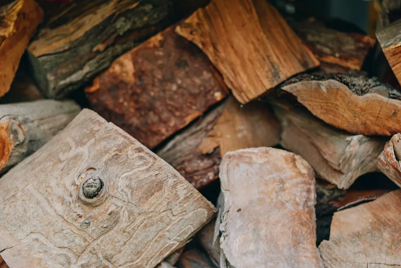Firewood woodpile chopped logs stacked wood split logs timber in closeup, rustic backyard pile for fireplace and cabin heating, autumn cozy atmosphere with warm tones and natural texture.