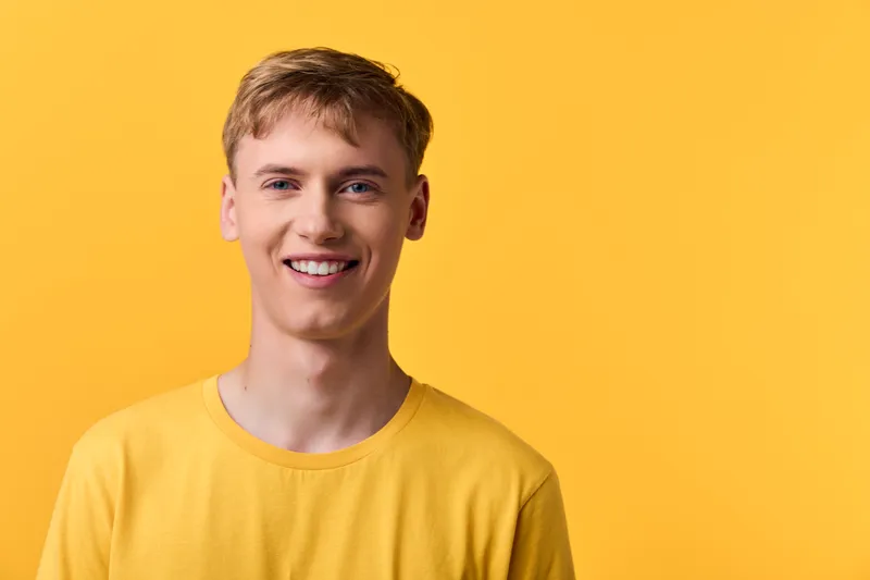 Man with a bright smile wearing a yellow shirt against a vibrant yellow backdrop, casual cheerful mood, clean studio lighting and color harmony for lifestyle or fashion concept