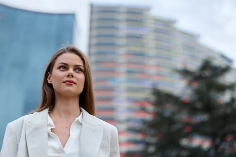 Confident woman in business attire outdoors, exuding professionalism amidst modern architecture, embodying empowerment and leadership in a corporate setting.
