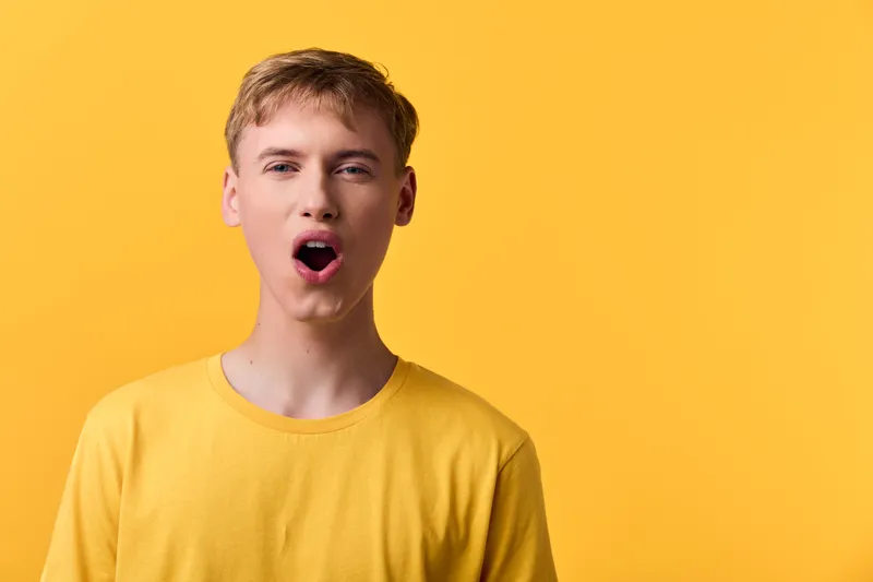 Surprised man wearing a yellow tee against a yellow backdrop, capturing a bold expression with an open mouth, bright studio lighting and vivid color for emotion and reaction in a minimal setup