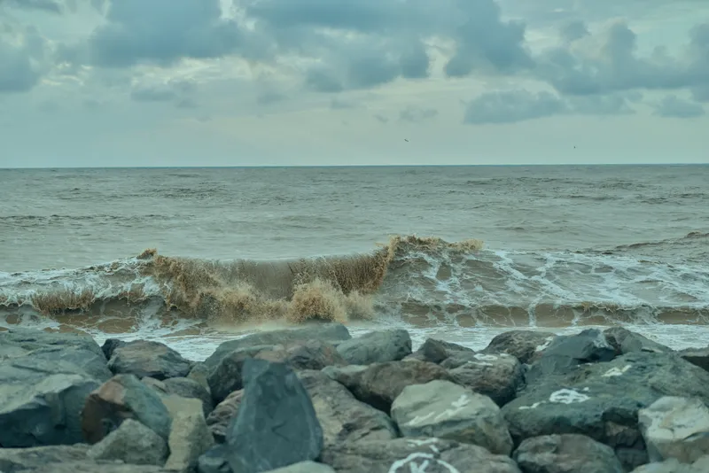 Rocky shoreline with crashing waves and a moody cloudy sky over the sea, a coastal landscape perfect for nature, travel, and ocean themed stock imagery