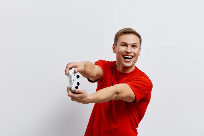 happy smiling young caucasian man wear red t-shirt hold gamepad play video games isolated white background digital detox entertainment concept