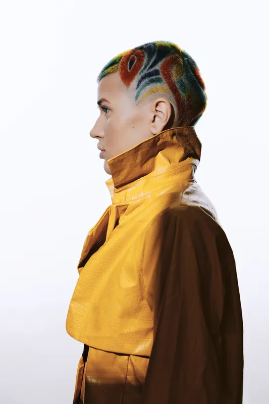 woman with colorful short hair and creative shaved design, wearing yellow jacket, profile portrait, modern fashion and artistic hairstyle in studio lighting
