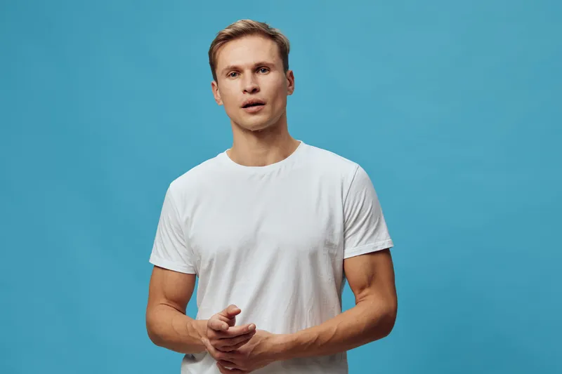 young man talk video call white t-shirt look at camera isolated blue background digital nomad lifestyle concept communication technology