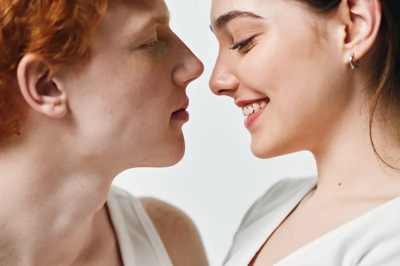 Couple, man and woman close together, intimate moment, smiling and facing each other, tenderness and affection between young people on white background.