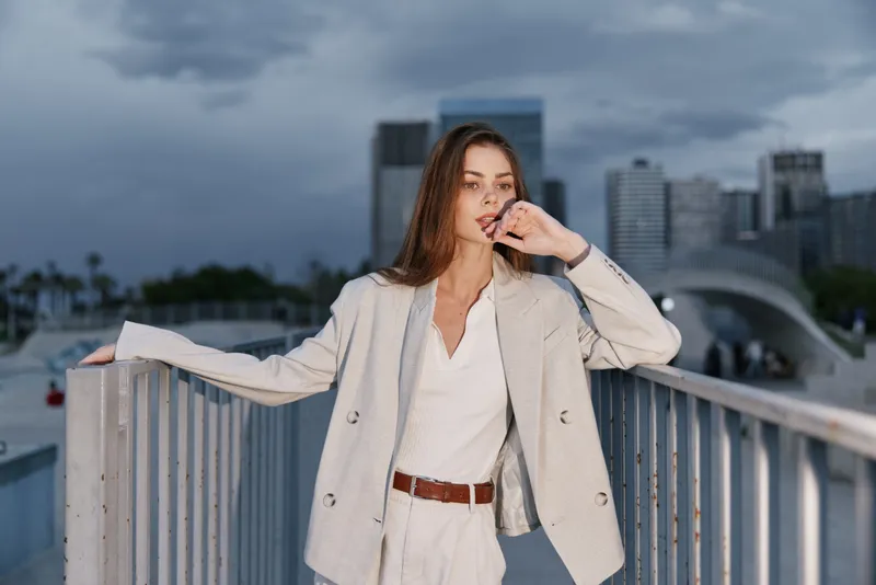 Confident woman in a light business suit on a city backdrop exuding professionalism and poise, showcasing modern business style and elegance.