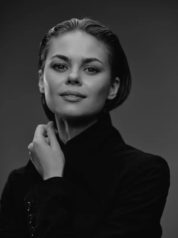 Black and white portrait of confident woman with natural expression wearing dark clothing and looking at camera.
