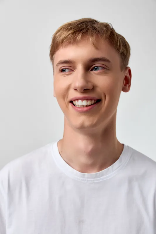 Smile, man, casual, happy, youth, closeup, studio, light, white shirt, cheerful expression and confident vibe in a bright clean setting