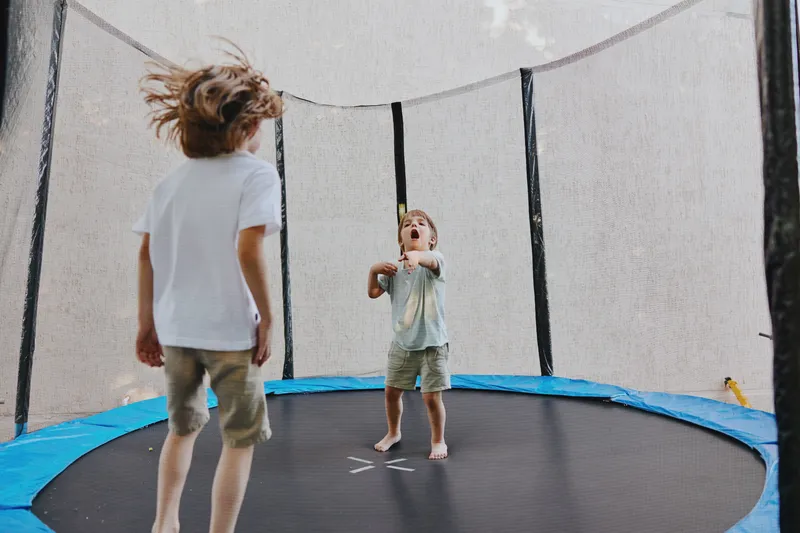 Excited boys jumping joyfully on a trampoline, showcasing energy and enthusiasm while playing outdoors on a sunny day, filled with laughter and fun.