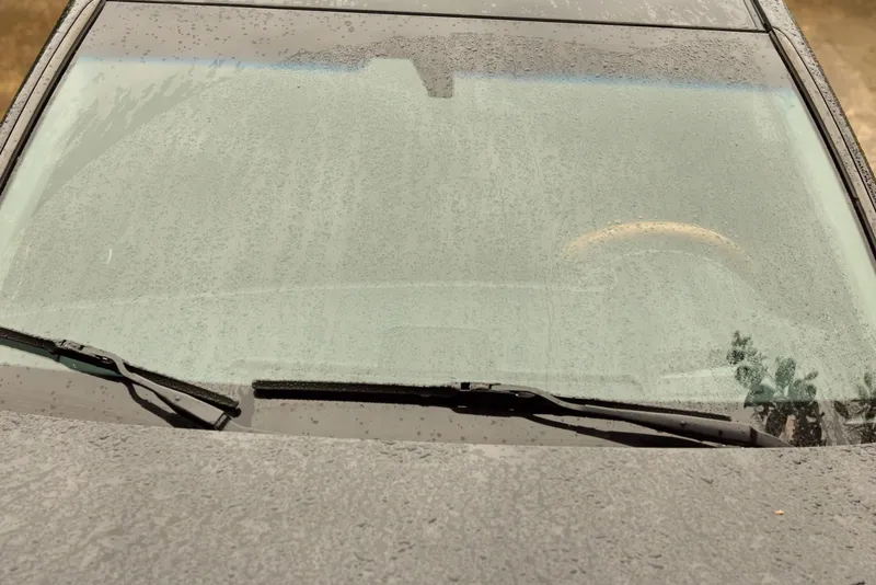 A frosted car windshield in the early morning reveals a quiet urban street, inviting reflection and a sense of winter calm