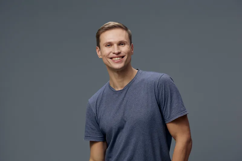 Smiling happy young caucasian man wear blue t-shirt look camera isolated on grey background casual portrait mental health and gadgets concept