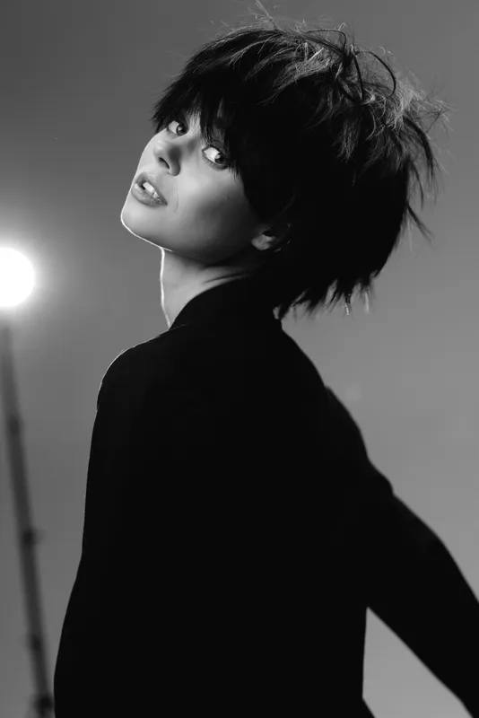 Black and white portrait of a stylish woman with short hair posing confidently in studio lighting.