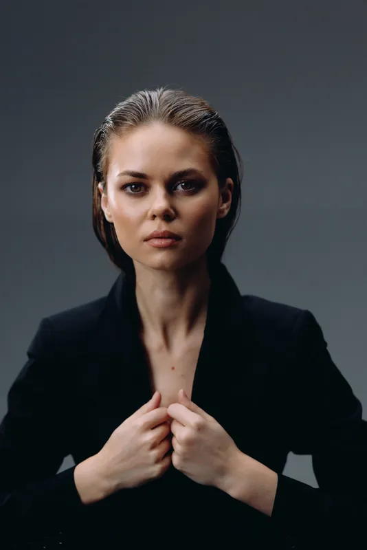 confident woman in black jacket with serious expression and dark background