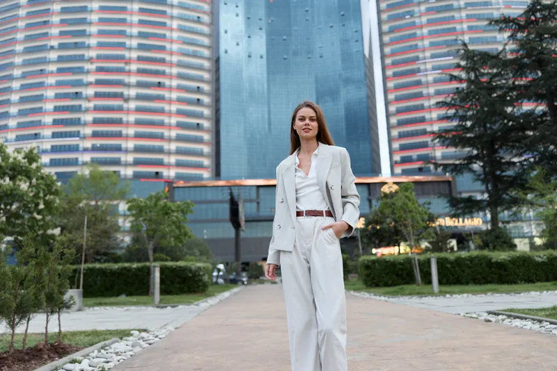 Confident businesswoman in a stylish suit walking in an urban setting, showcasing modern professionalism and elegance.