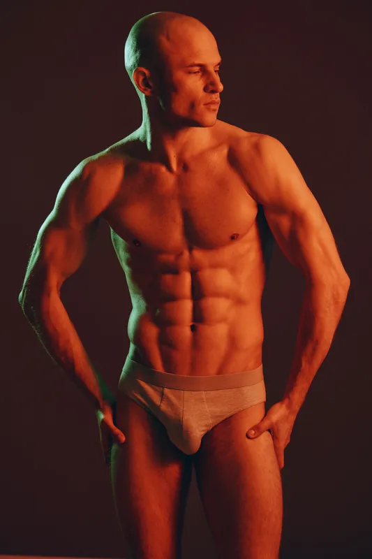 Fit man posing confidently in stylish underwear, showcasing toned physique against a vibrant backdrop. The image captures strength and confidence beautifully.