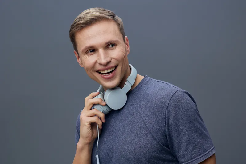 smiling man with headphones wear casual blue t-shirt look side happy cheerful communication concept digital detox technology lifestyle isolated gray background