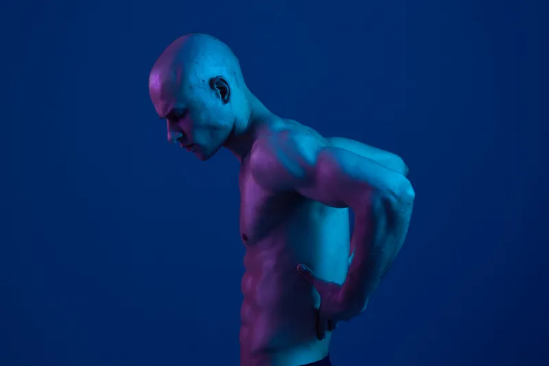 Muscular man with a focused expression, displaying strong emotions in a vibrant blue tone. Perfect for concepts related to strength and determination.