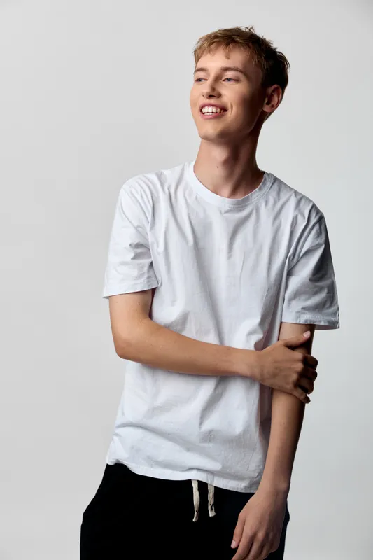 Young man in a white t shirt with a bright smile, casual pose, studio lighting, and upbeat vibe, showcasing relaxed style and everyday confidence