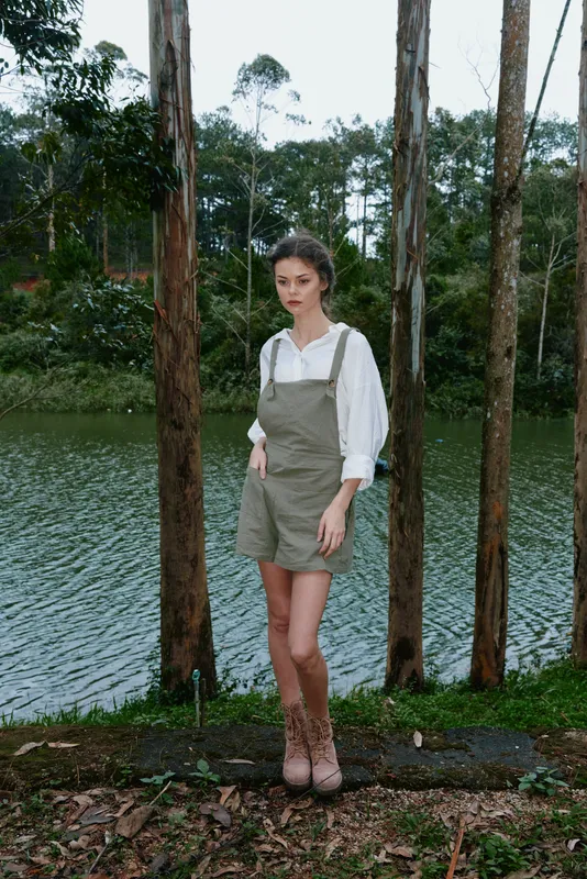 Young woman in a casual outfit, standing by the lake amidst greenery, expressing calmness and serenity with natural surroundings, perfect for nature themed projects
