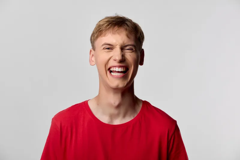 Laughing, smile, man, red shirt, joy, happiness, expression, upbeat, energy, casual moment of a young man captured in a bright, joyful mood, perfect for lifestyle or marketing content seeking