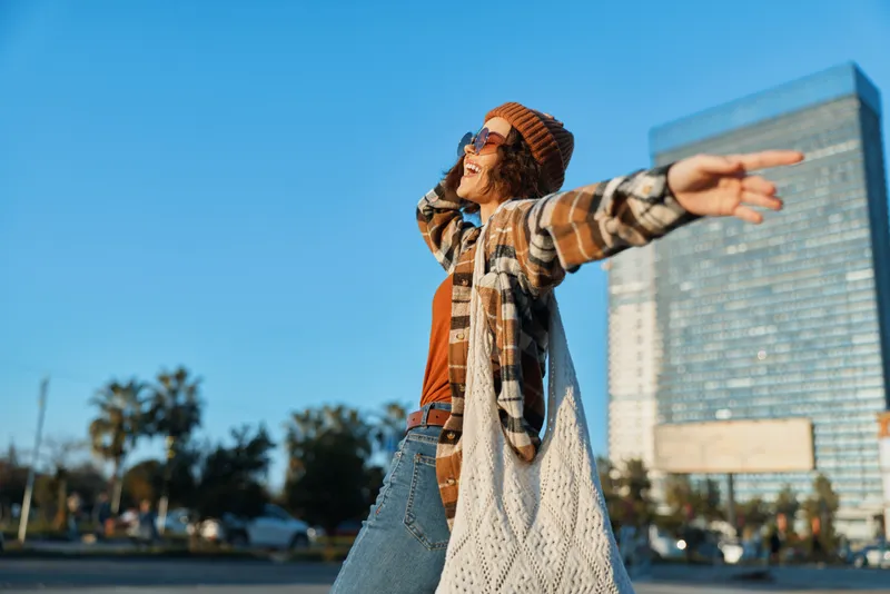 Woman arms urban sunlight carefree bohemian portrait of a young woman spreading arms on city street at golden hour glow, authenticity, candid lifestyle and emotional storytelling.