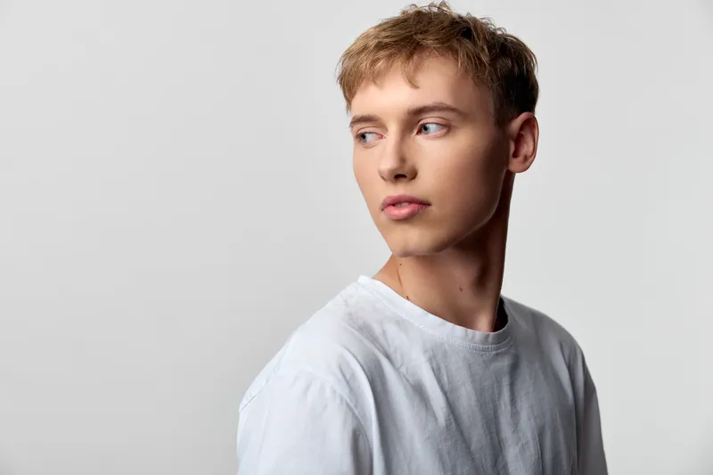 Man profile looking away in a white tshirt, studio lighting highlights a clean background and calm mood, minimal fashion lifestyle image for modern editorials