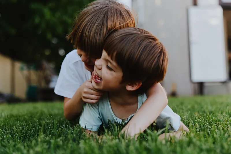 Happy children playing together, enjoying laughter on a sunny day in a green grass field, capturing the essence of childhood joy and friendship.