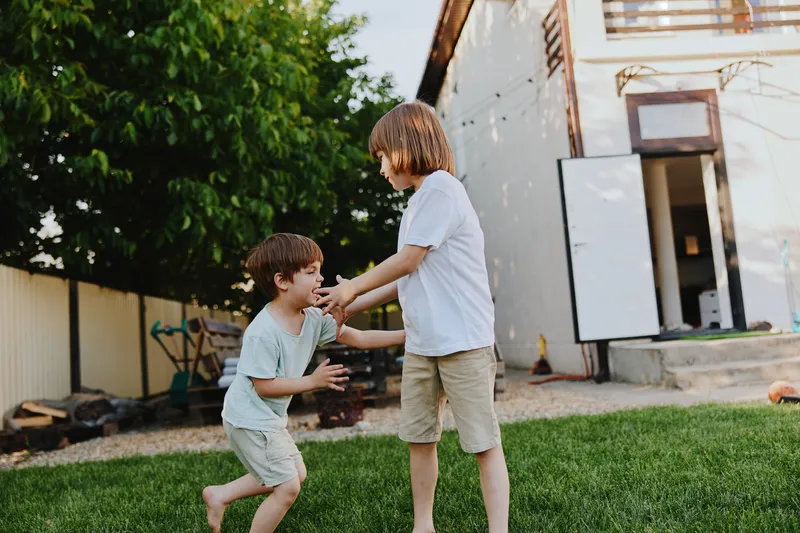Two happy boys playing together in a sunny backyard, showcasing the joy of childhood and friendship in a vibrant, playful atmosphere.