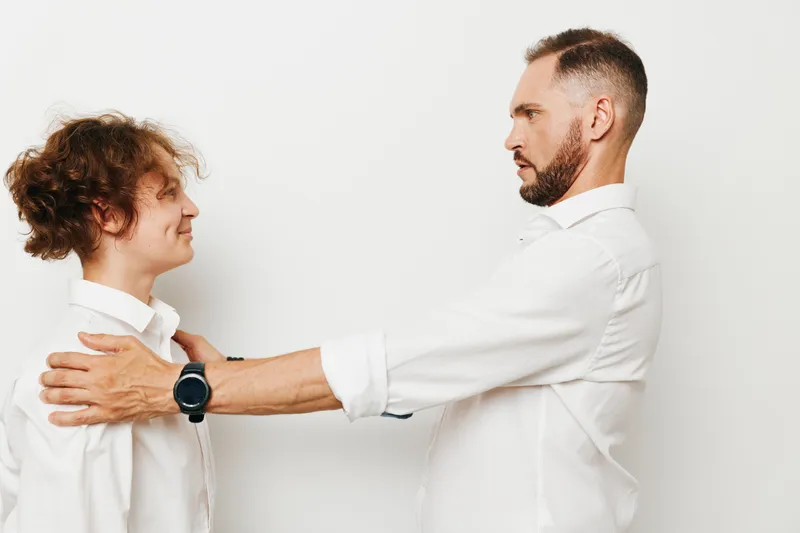 A male business professional stands against an isolated colored background, facing another man. Confidence and focus convey leadership and collaboration during negotiation.