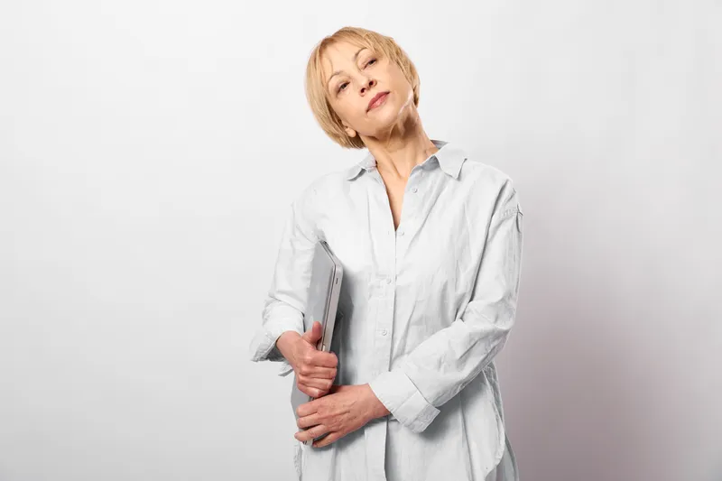 Elderly woman doctor,white coat,holding medical syringe,gentle smile,studio portrait on light gray background,vaccination and healthcare concept,calm mood