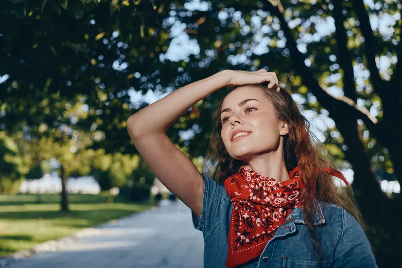 lifestyle woman in modern boho-western denim street style wearing red bandana outdoors with bright film color sunlight and natural background