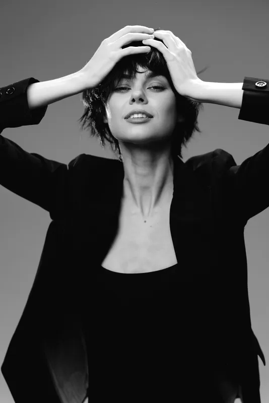 Black and white portrait of a stylish woman with short hair in a blazer expressing confidence and sophistication.