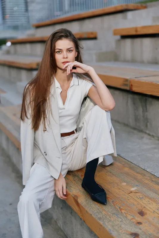 stylish young woman in white business casual outfit sitting on urban wooden stairs, thoughtful expression, natural light, outdoor fashion portrait