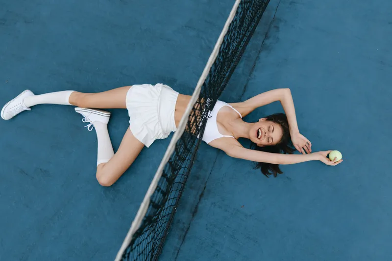 Energetic young model in activewear enjoying tennis on the court, showcasing excitement and joy with a bright color palette and dynamic poses, perfect for sports and fitness concepts