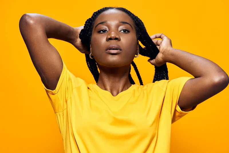 Confident Black Woman in Yellow T Shirt Posing Against a Bright Yellow Background