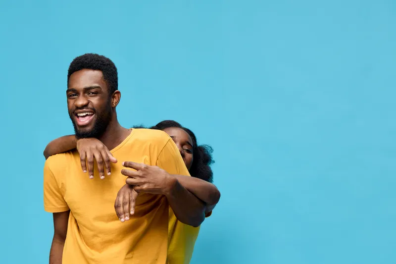 Happy young couple smiling against a bright blue background, showcasing joy and connection, perfect for lifestyle and relationship concepts