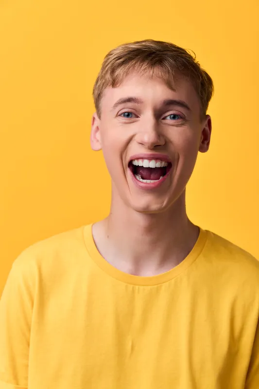 Joyful man with a wide smile in a bright yellow shirt, radiating upbeat energy and casual confidence, ideal for lifestyle branding and advertising, vibrant color aesthetics and positive mood