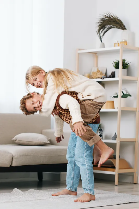 Authentic lifestyle moment capturing a couple sharing a playful piggyback indoors, highlighting genuine connection, warmth, and everyday joy in a cozy, sunlit home setting.