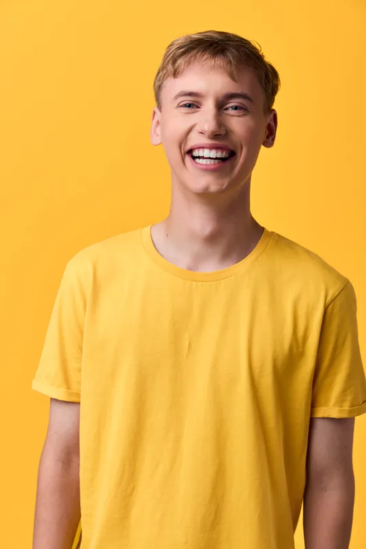 Smiling man in a bright yellow t shirt against a bold background, conveying cheerful energy, casual style, and approachable mood.