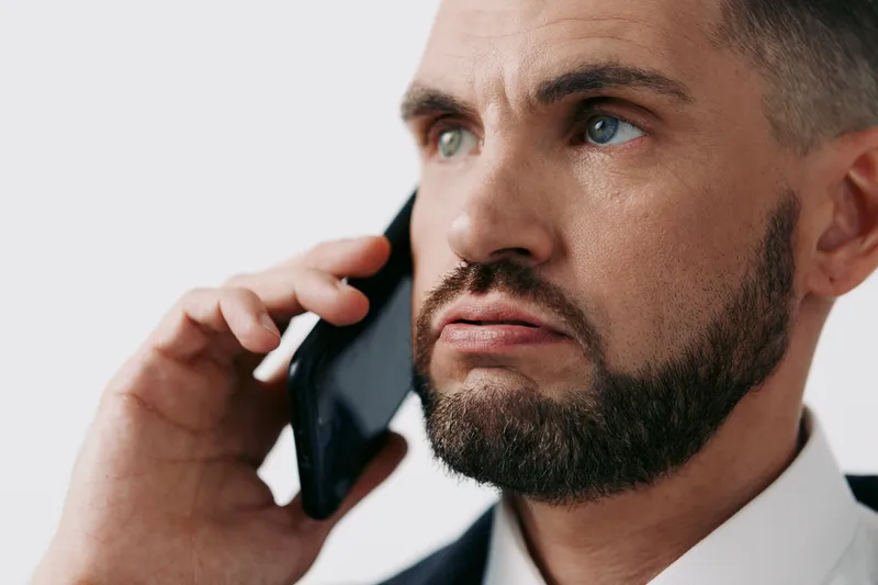 Professional man on a colored isolated background, speaking on a mobile phone with a focused expression, portraying business confidence, leadership, and effective communication.